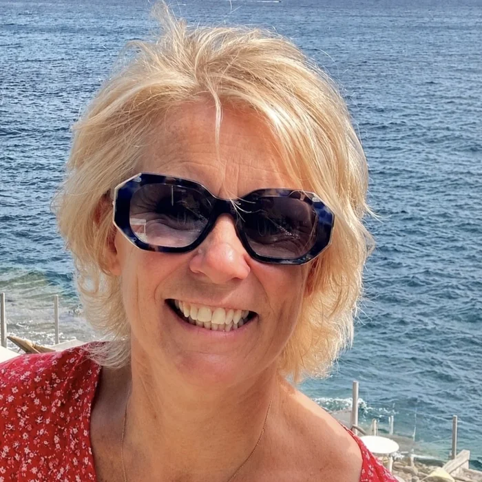 Valérie Parisset en lunettes de soleil, souriante, au bord de la mer